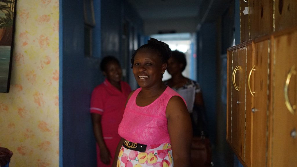 Lydiah in the hallway of St. George's where she has worked for four years with two nurses in the background.