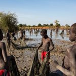 Hundreds of children displaced by fighting in Sudan and South Sudan look for mudfish in a seasonal lake near the town of Yida, South Sudan. The little money they earn from selling the fish helps support their families — and sometimes pays their school fees. © Andrew McConnell