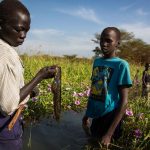 Kir Buth, 15, holds a fish caught moments earlier at a swamp near Yida, as Guor Path, 14, and Dictor Arak, 15, look on. Displaced by the fighting in South Sudan, the boys fish with their friends to raise money for schoolbooks and school fees.

