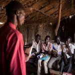 Second from right, Dictor Arak, 15, joins other students in a class at Yida Refugee Primary School in Yida, South Sudan. Dictor, who dreams of becoming a doctor, pays for his schoolbooks with the money he earns from catching and selling mudfish. © Andrew McConnell