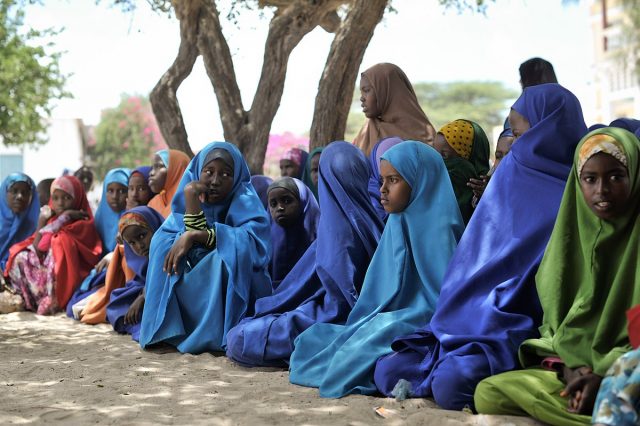 Young girls watch a football game being played outside of their school during breaktime at a center run by Dr. Hawa in the Afgoye corridor, Somalia. Dr. Hawa, an internationally recognized humanitarian, established the Hawa Abdi Center in 1983, and has catered for tens of thousands over the years displaced by civil war in Somalia. The center now contains an IDP camp, a school, and a hospital. (Photo credit: AMISOM Public Information/Tobin Jones)
