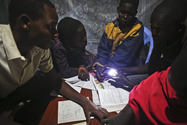 John Keko Mututua, age 16, left, studies with other children in his uncle's eco manyatta, a traditional home that has a solar panel which provides electricity after dark, in the town of Susua, Kenya. (Photo credit: Tara Todras-Whitehill)